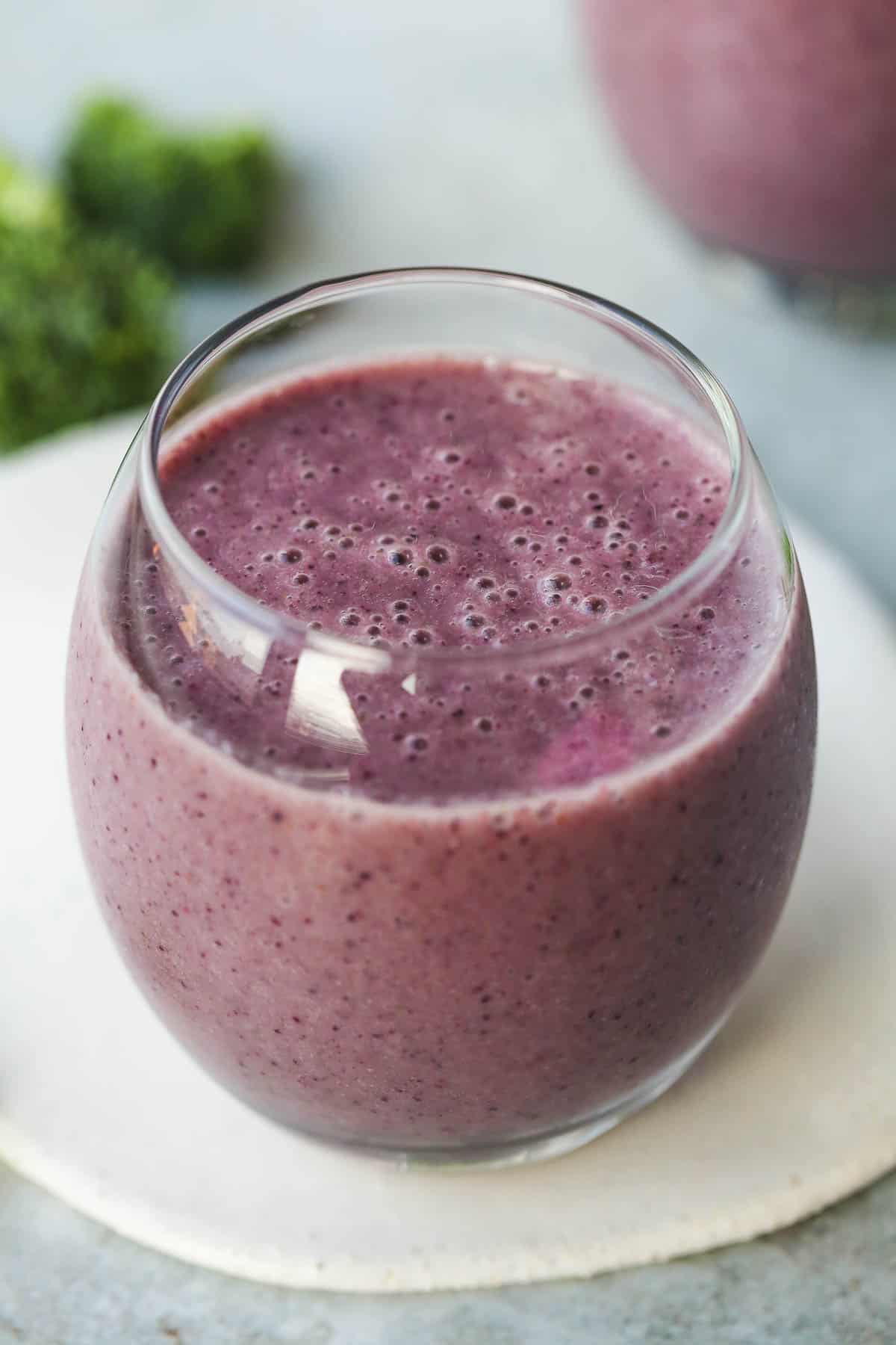 Mouthwatering smoothie served in a glass that's placed over a plate.