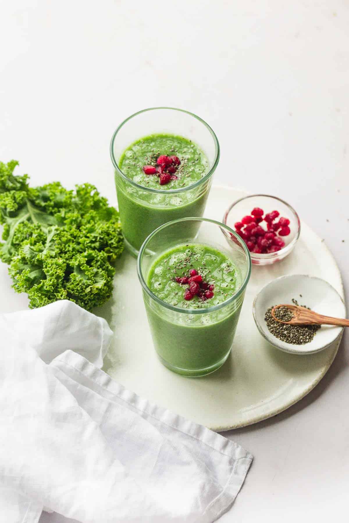 Glasses filled with green smoothie on a ceramic white tray