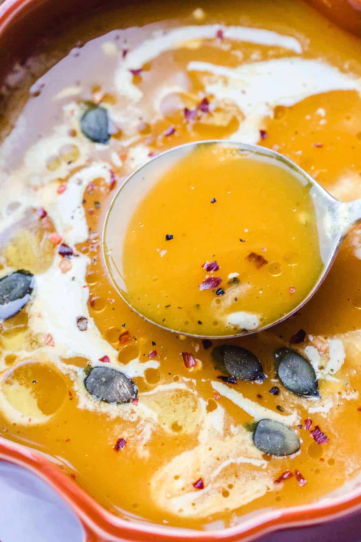 Vegan Pumpkin Soup garnished with fresh thyme, child flakes and pumpkin seeds