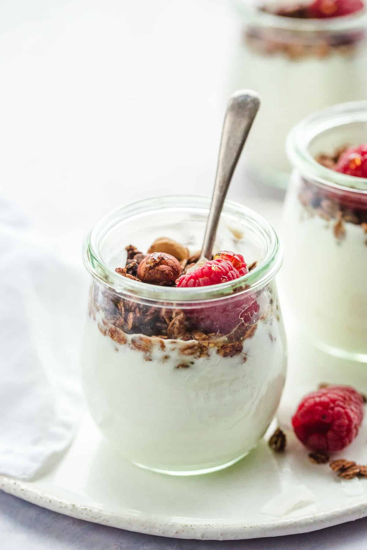 A small Weck jar with yogurt, granola, nuts, raspberries.