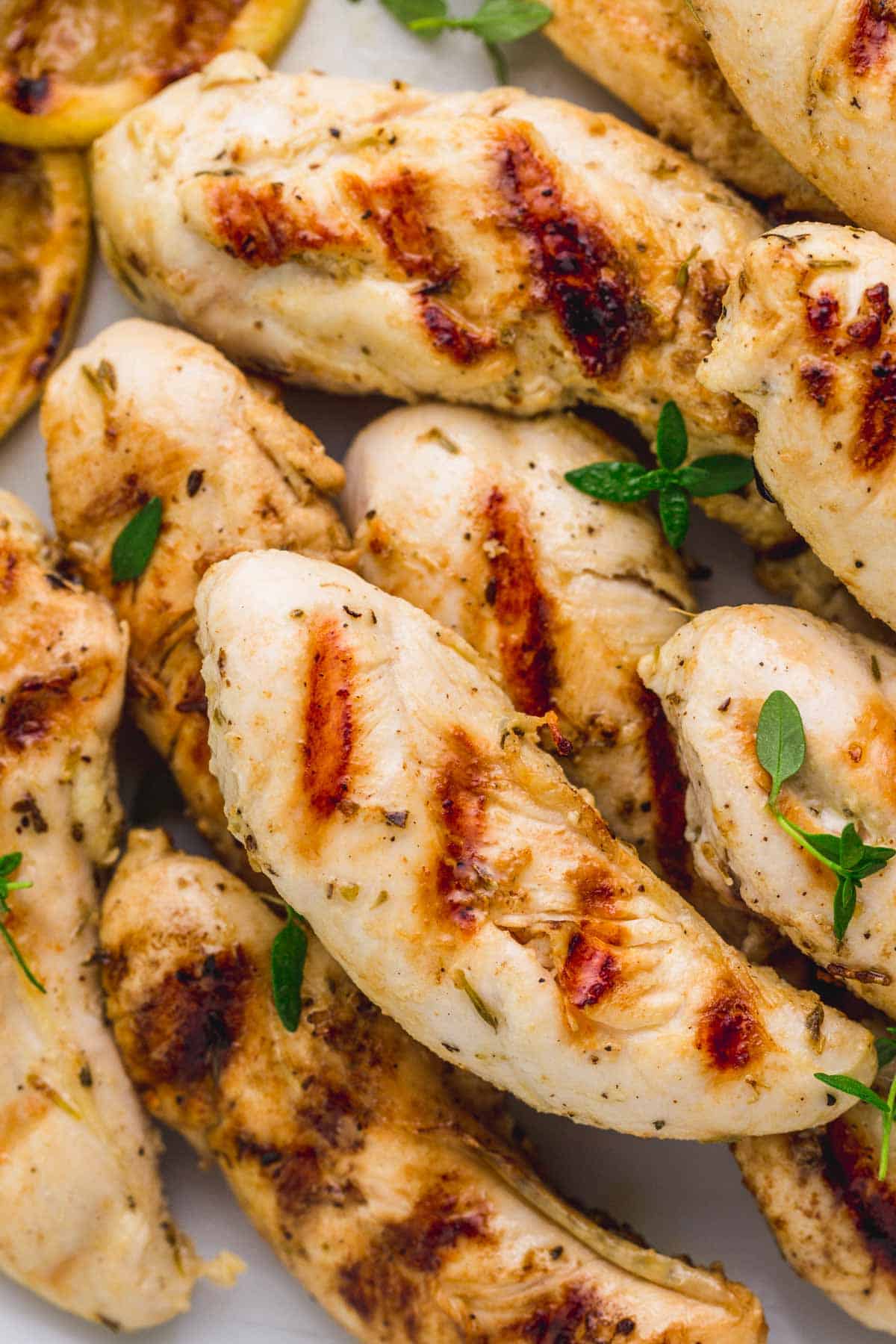 Close up of grilled chicken tenders and fresh thyme leaves