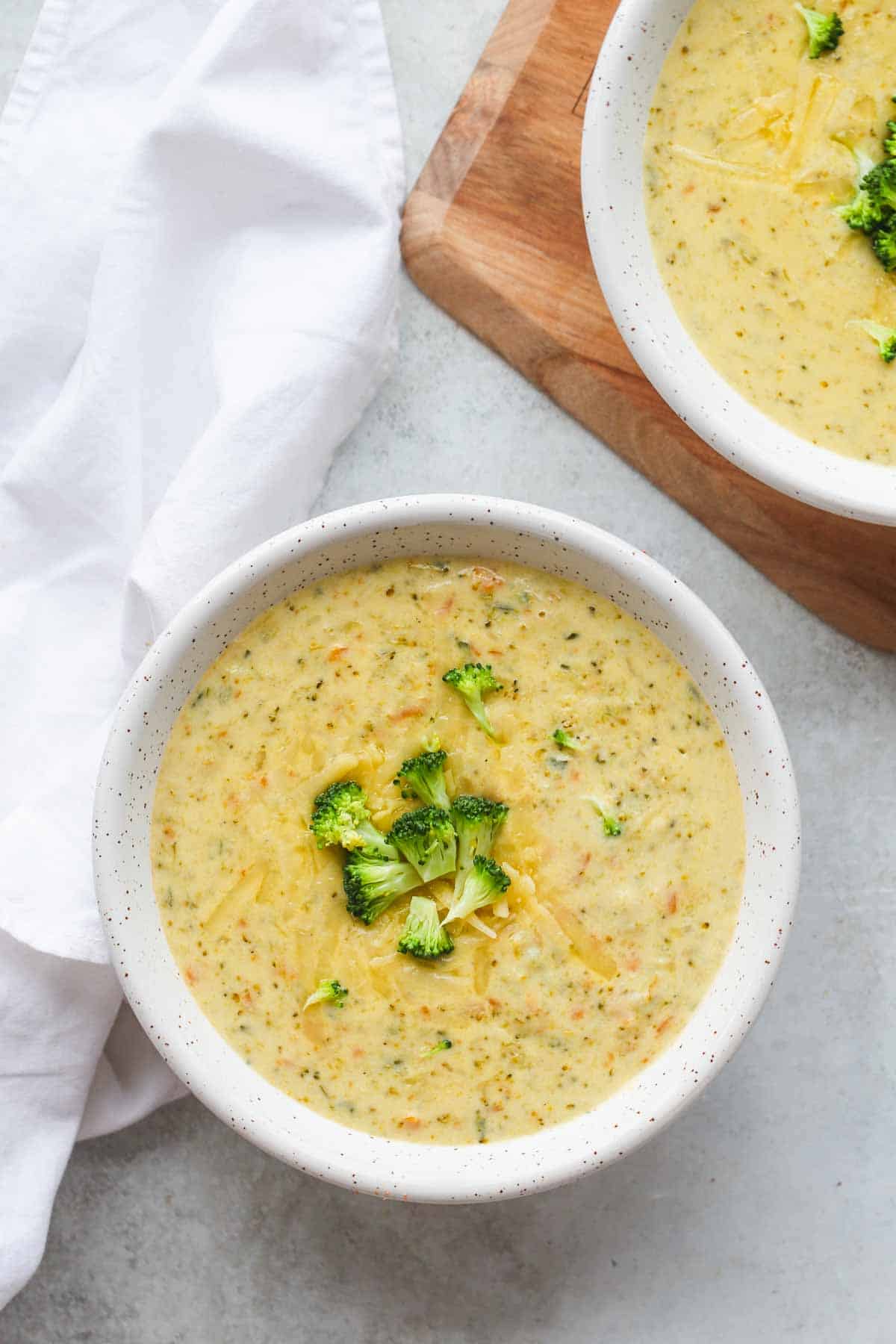 Instant Pot Broccoli Cheddar Soup served in 2 white bowls and decorated with small broccoli florets 