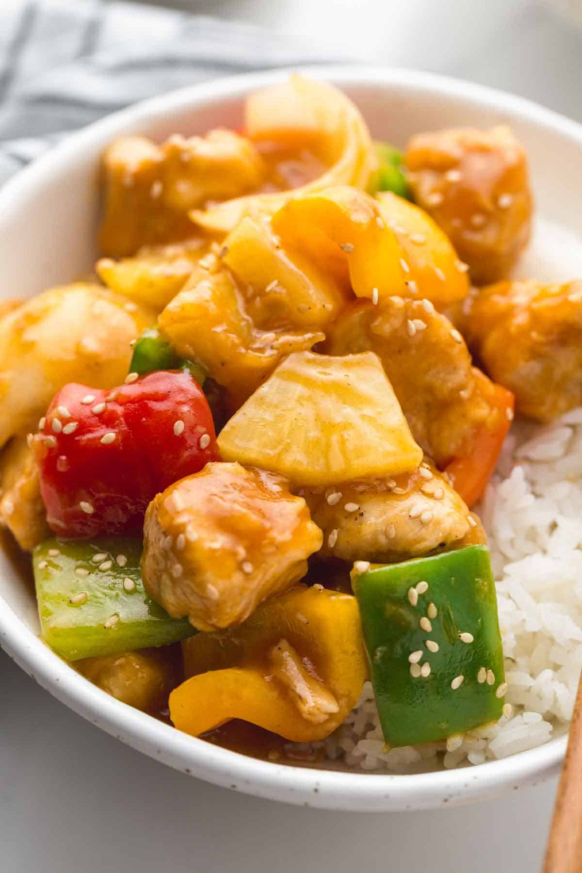 Sweet And Sour Chicken served over rice in a white bowl