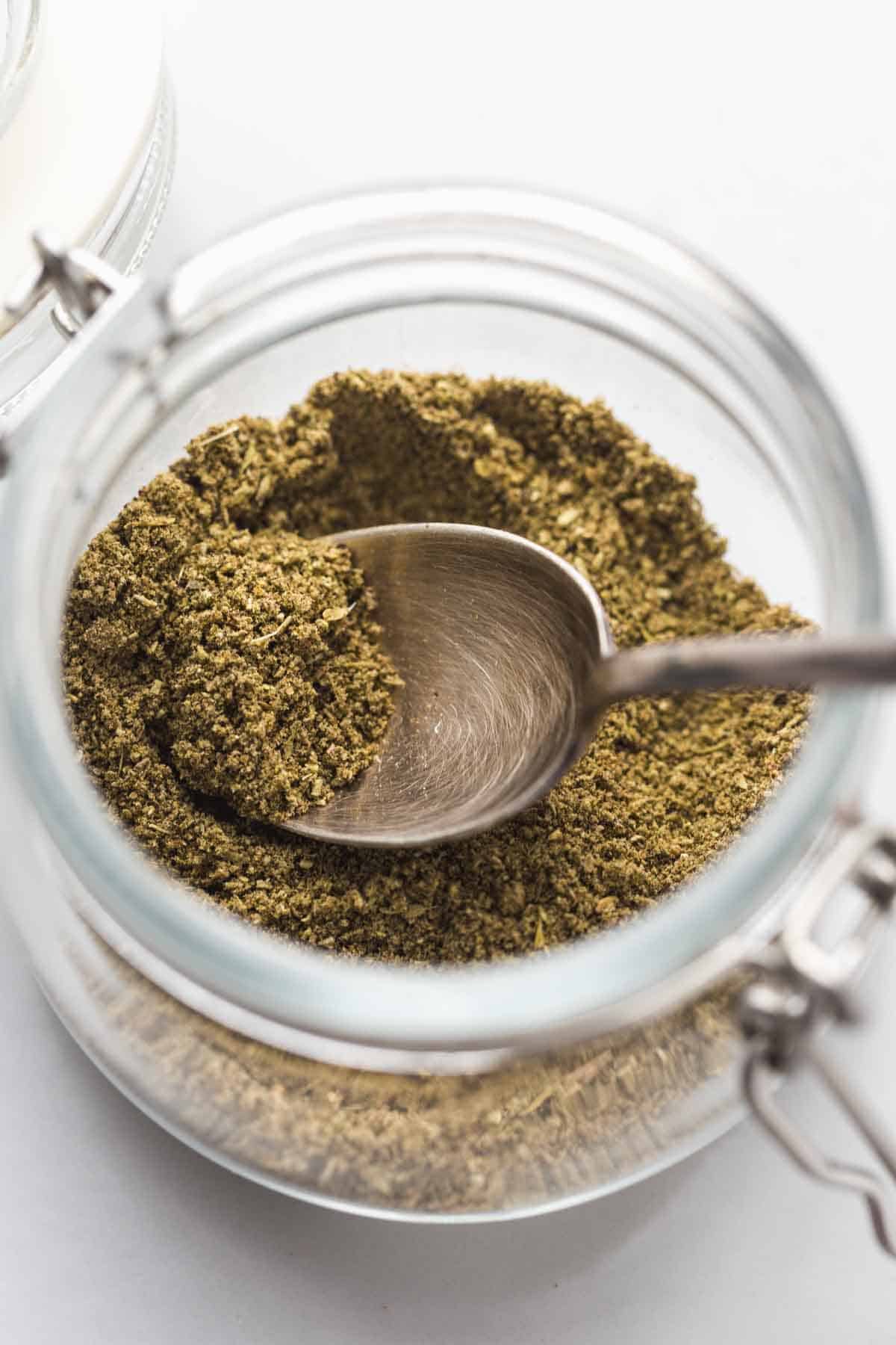 Homemade Poultry Seasoning in a jar with a spoon