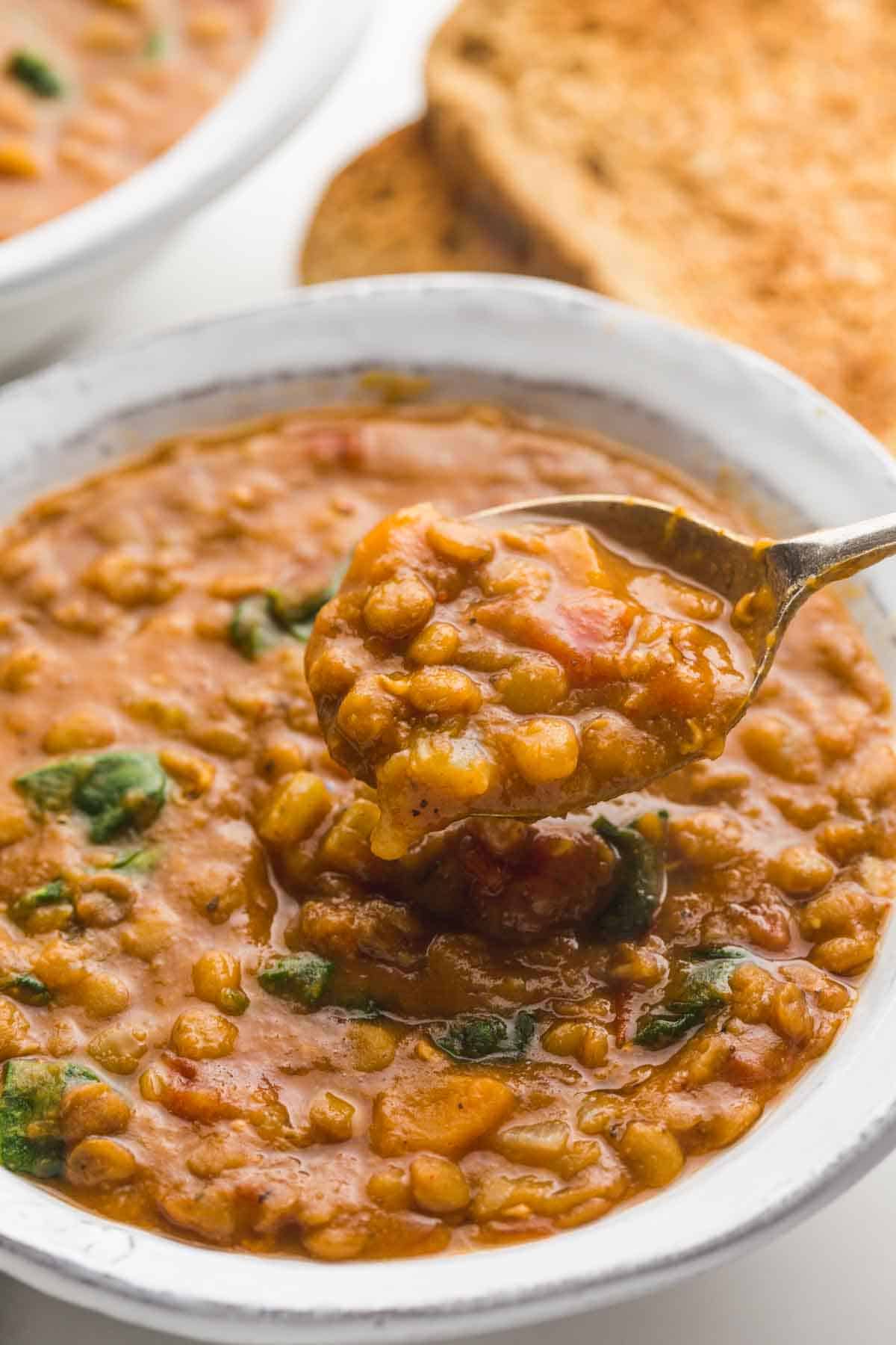 A close up of a spoon filled with mouthwatering Instant Pot Lentil Soup 