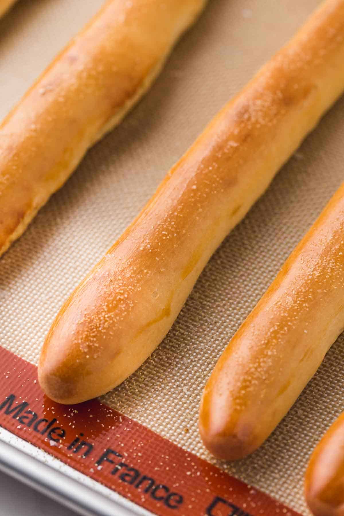 Shiny breadsticks with garlic powder sprinkled, on a silicone baking mat