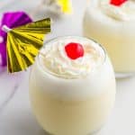 Piña Colada in 2 glasses with whipped cream and maraschino cherries, and cocktail umbrellas