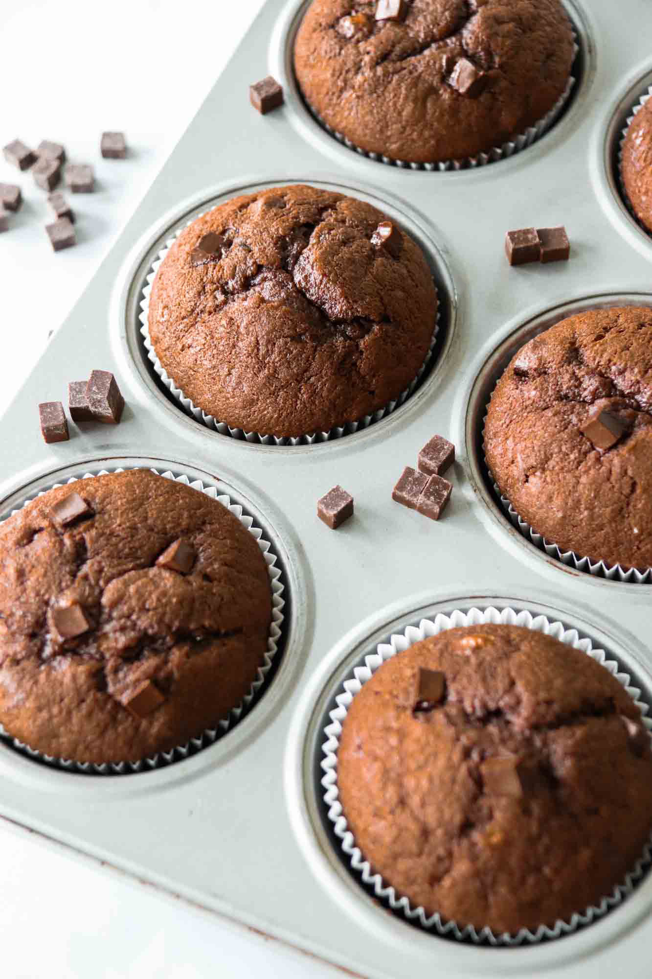 Chocolate banana muffins in a muffin tin with chocolate chunks