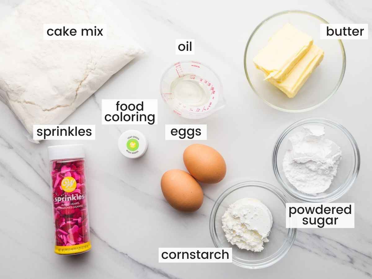 Overhead shot of ingredients needed to make these Christmas cookies including cake mix, butter, eggs, sugar, cornstarch, food coloring and sprinkles.