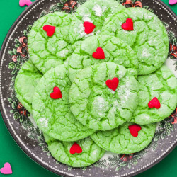 Overhead shot of grinch cookies on a plate, with heart sprinkles on the sides