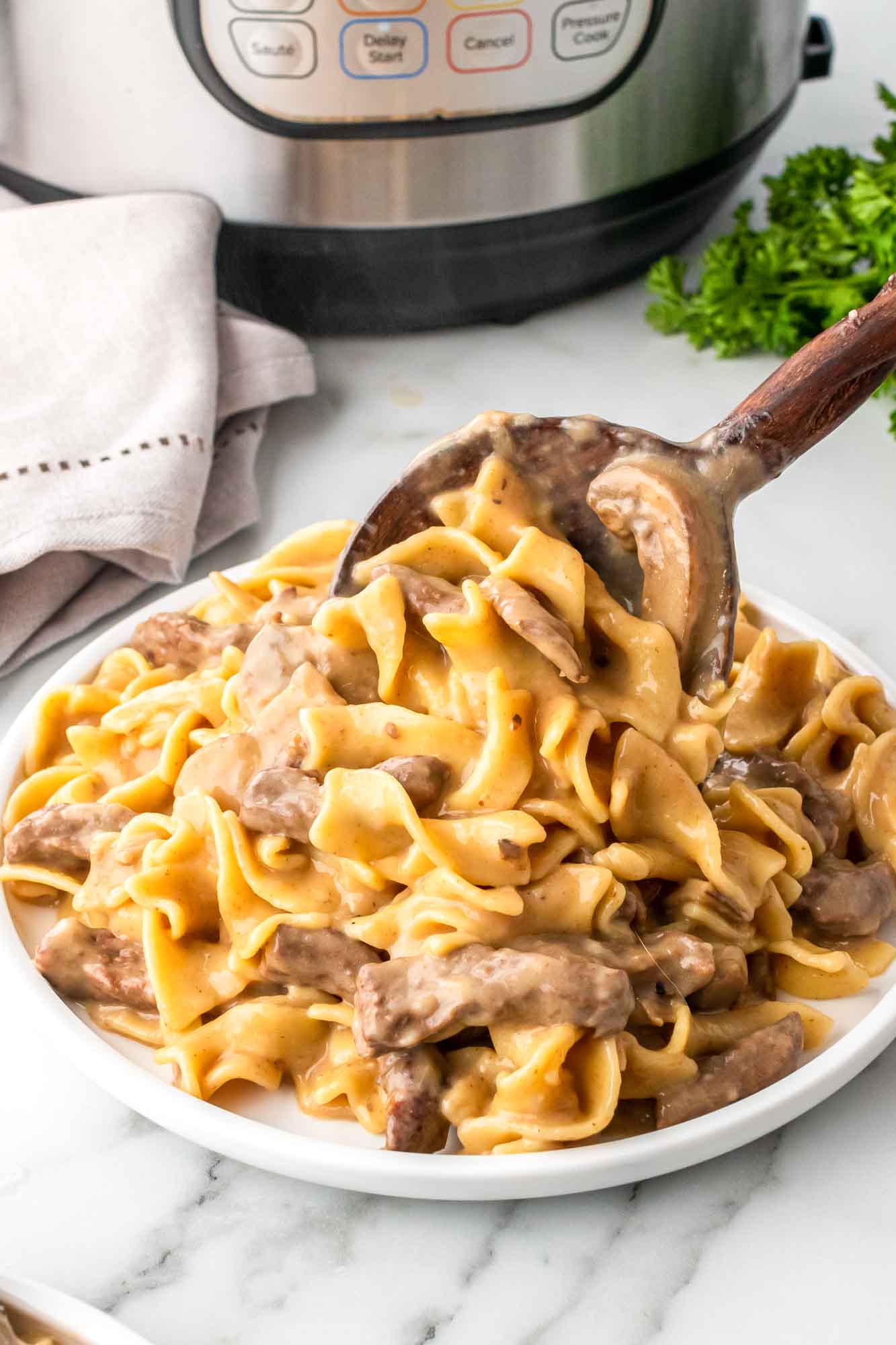 Creamy Beef Stroganoff cooked in an Instant Pot and served with a wooden spoon