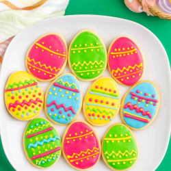 Overhead shot of decorated easter egg sugar cookies on a square white plate
