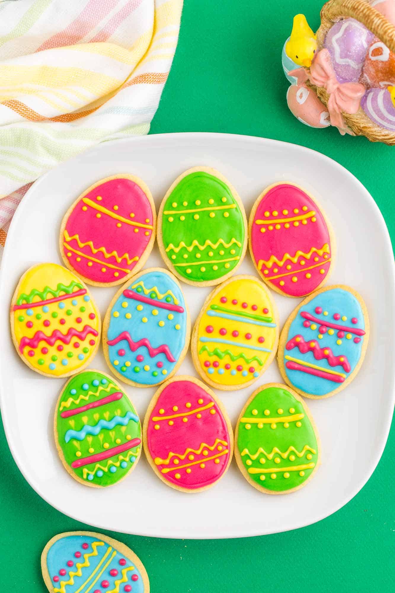 Overhead shot of decorated easter egg sugar cookies on a square white plate