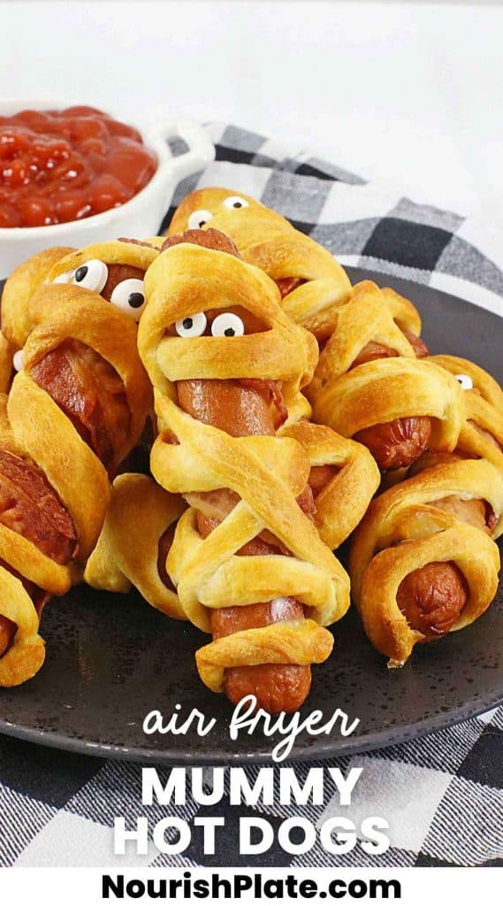 Mummy hot dogs with candy eyes on a black plate, and overlay text that says "Air fryer mummy hot dogs"