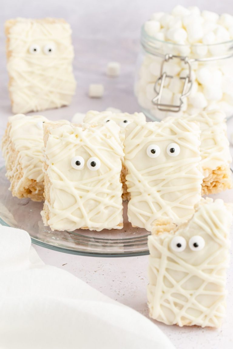 Mummy Rice Krispie Treats with candy eyes, standing on a glass plate.