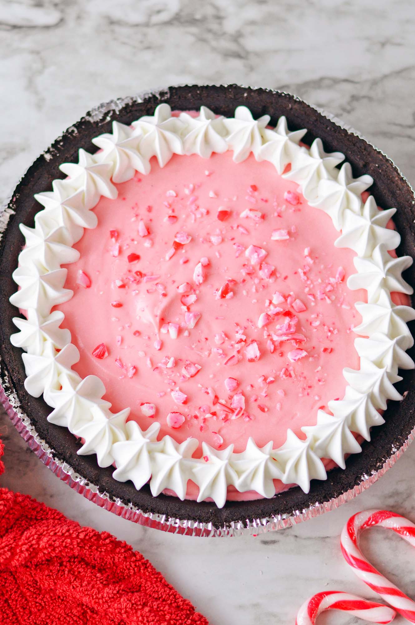 Overhead shot of a chocolate peppermint pie with crushed candy cane and whipped cream decorations