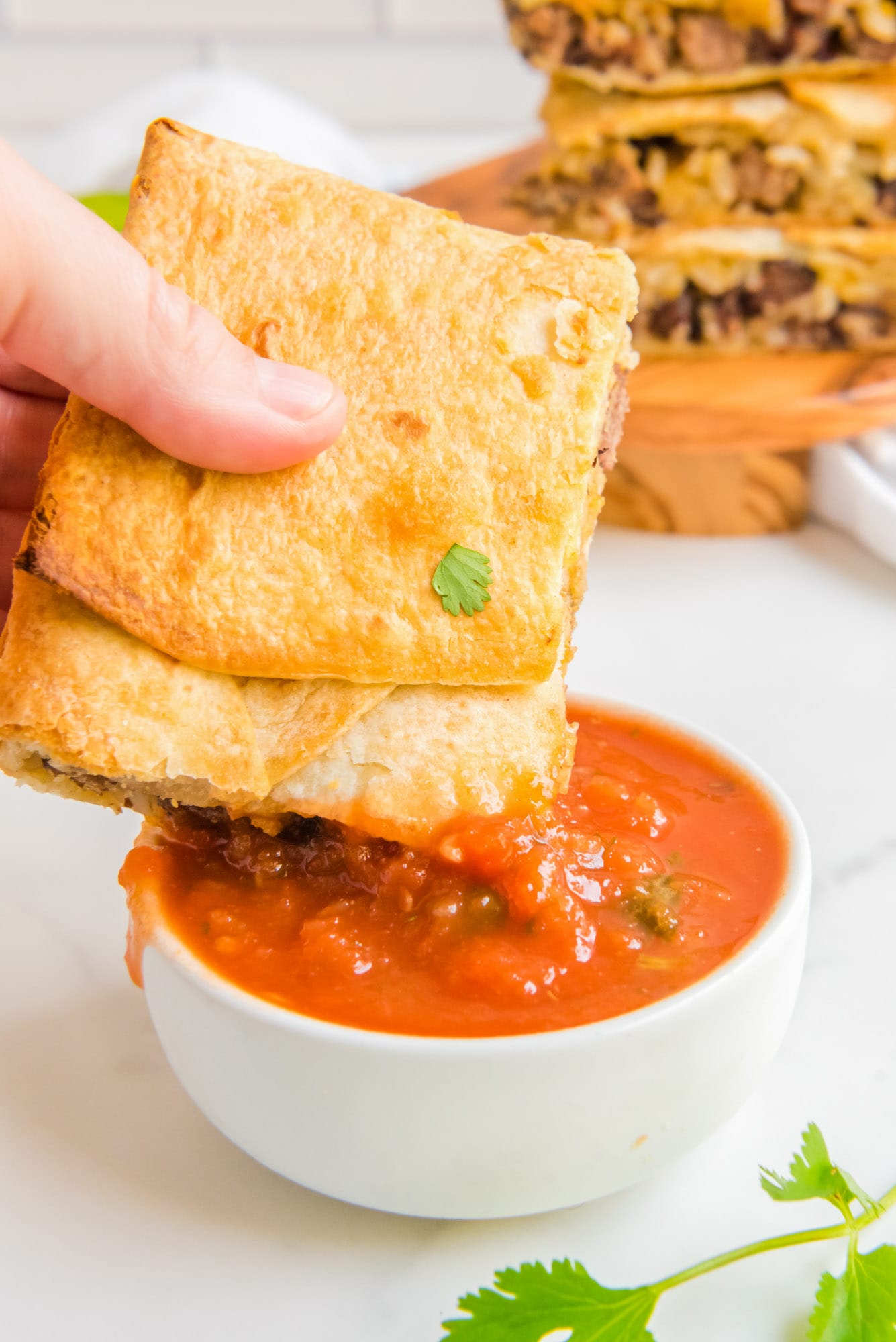 Dipping a square of quesadilla in salsa