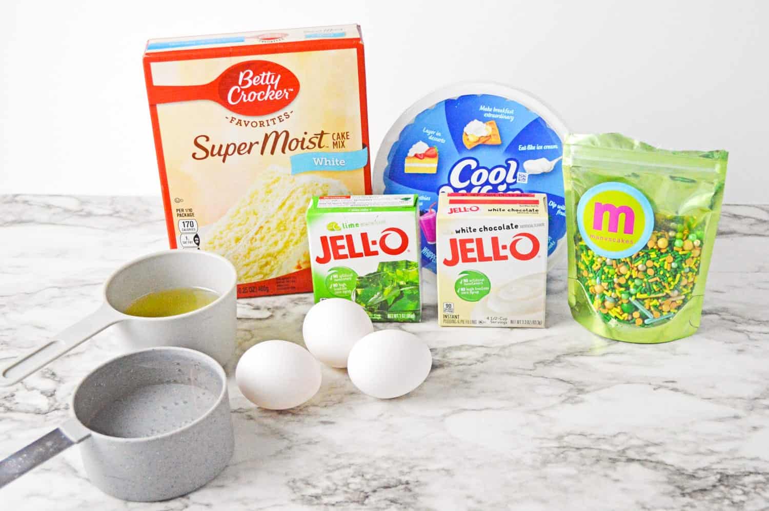 Ingredients needed to make lime jello poke cake including cake mix, whipped topping, eggs, and jello.