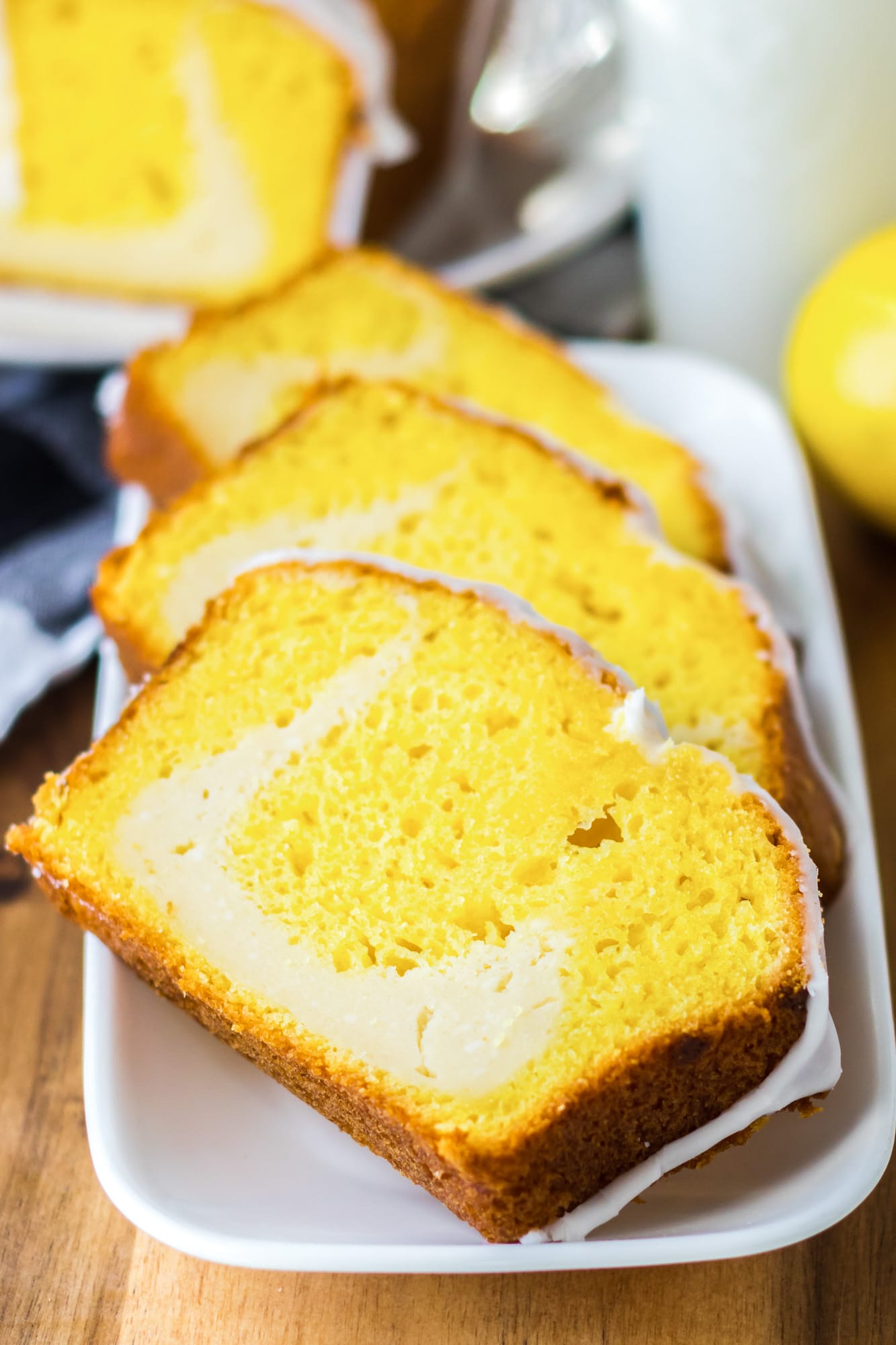 Slices of lemon cheesecake loaf on a white rectangular plate