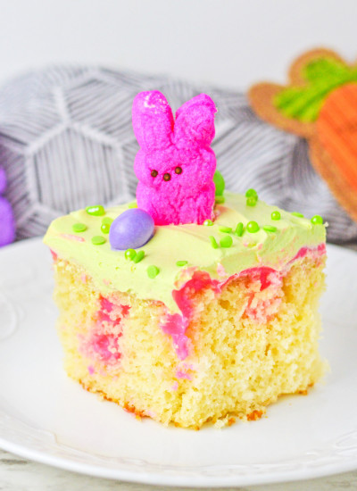 A slice of vanilla poke cake with easter peep and an easter egg