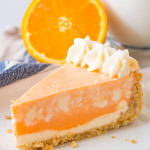 A slice of orange creamsicle cheesecake served on a white plate