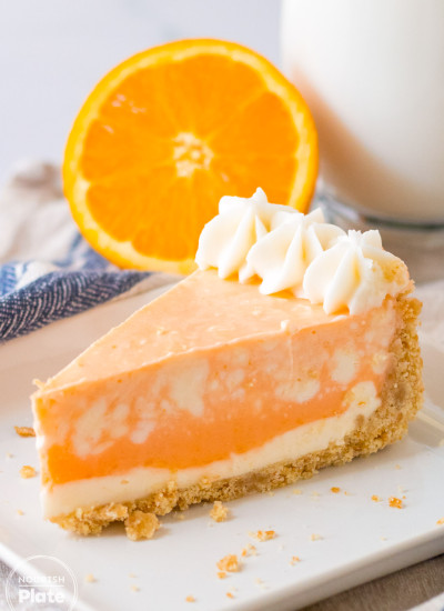 A slice of orange creamsicle cheesecake served on a white plate