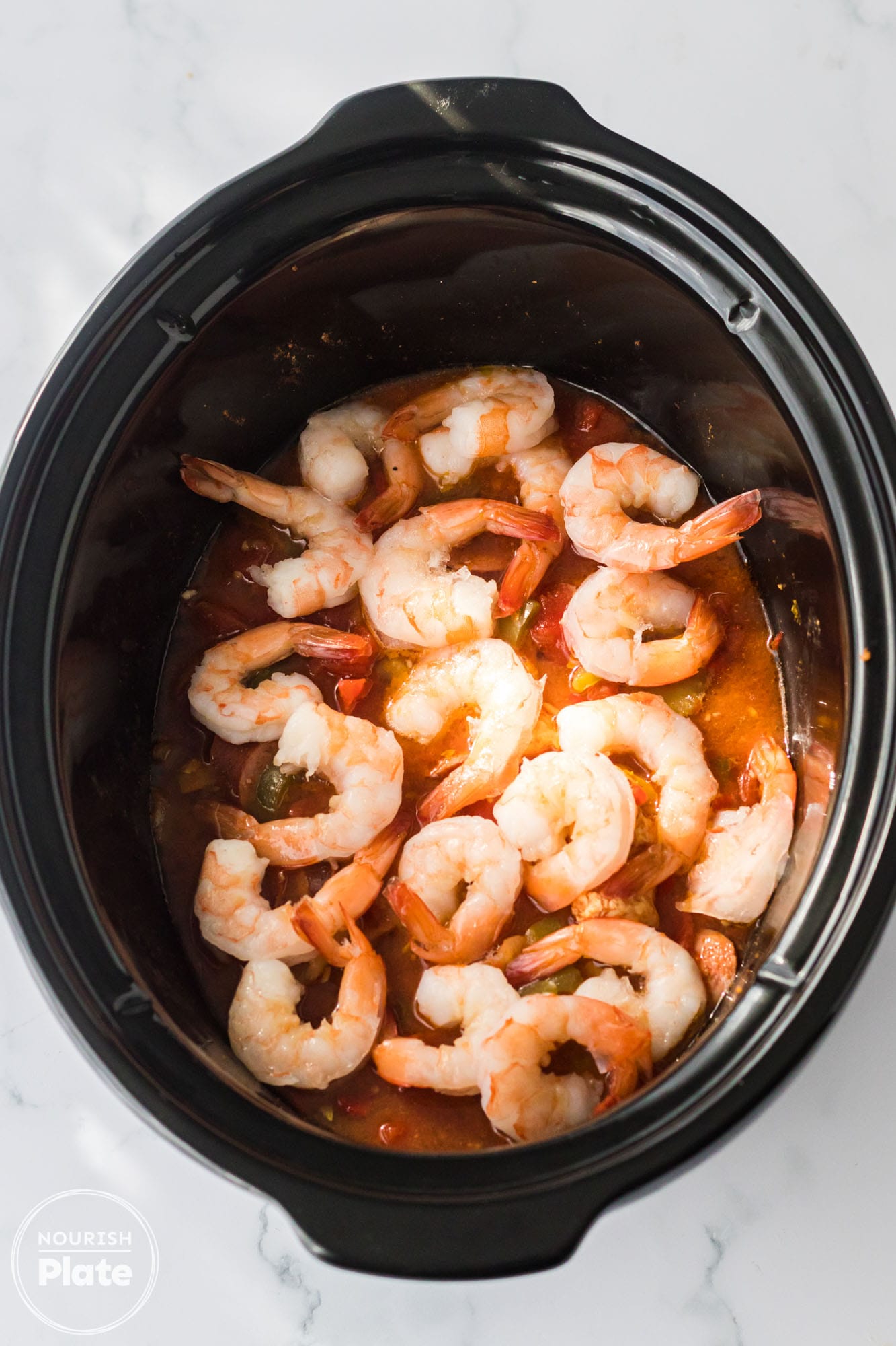 Shrimp and cajun sauce in a black slow cooker