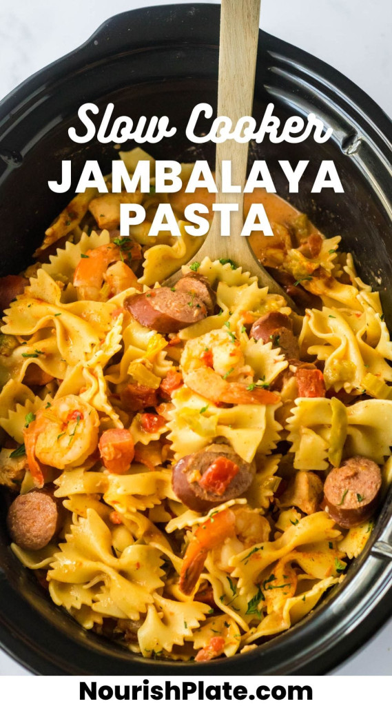 Overhead shot of jambalaya pasta in a black slow cooker with a wooden spoon, and overlay text that says "Slow Cooker Jambalaya Pasta"