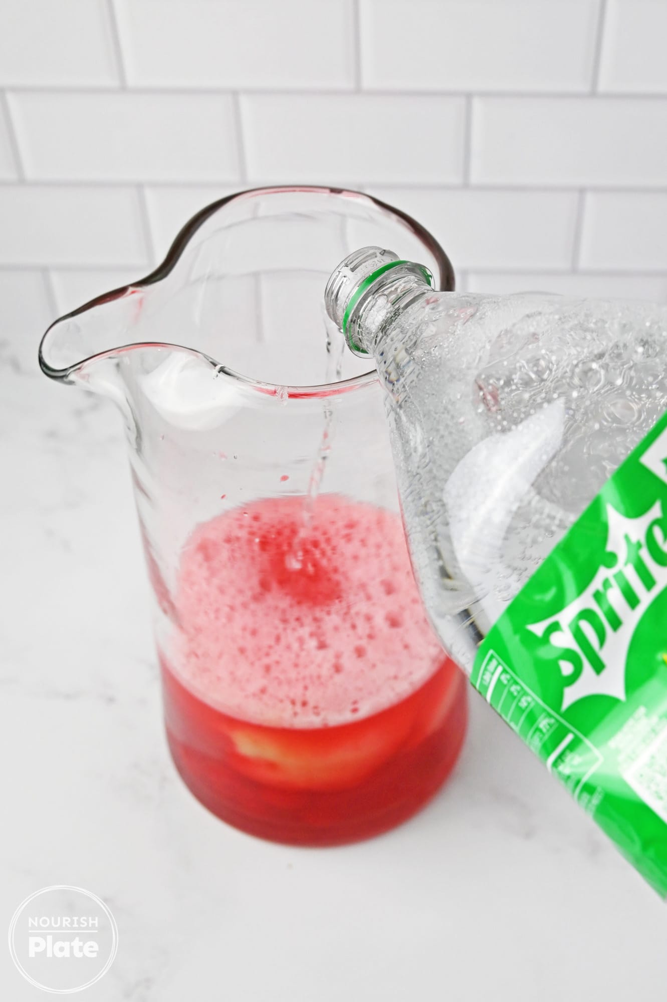 Pouring sprite in a pitcher with cherry juice and lemonade