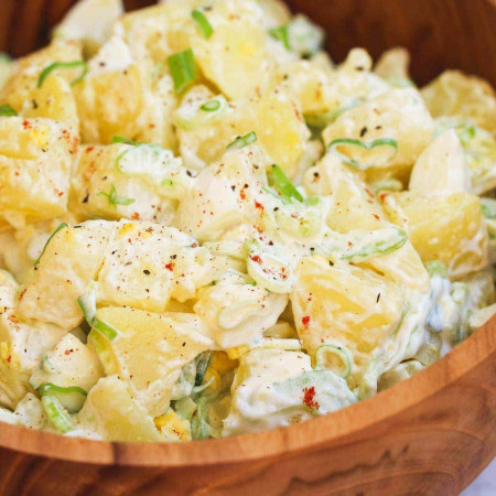 Close up shot of potato salad in a wooden bowl