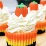 Mini candy corn cheesecake topped with whipped cream and a candy pumpkin