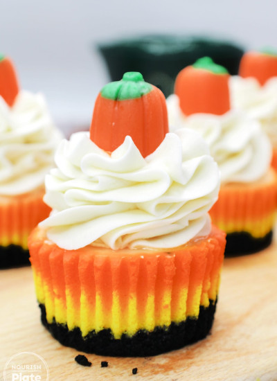 Mini candy corn cheesecake topped with whipped cream and a candy pumpkin