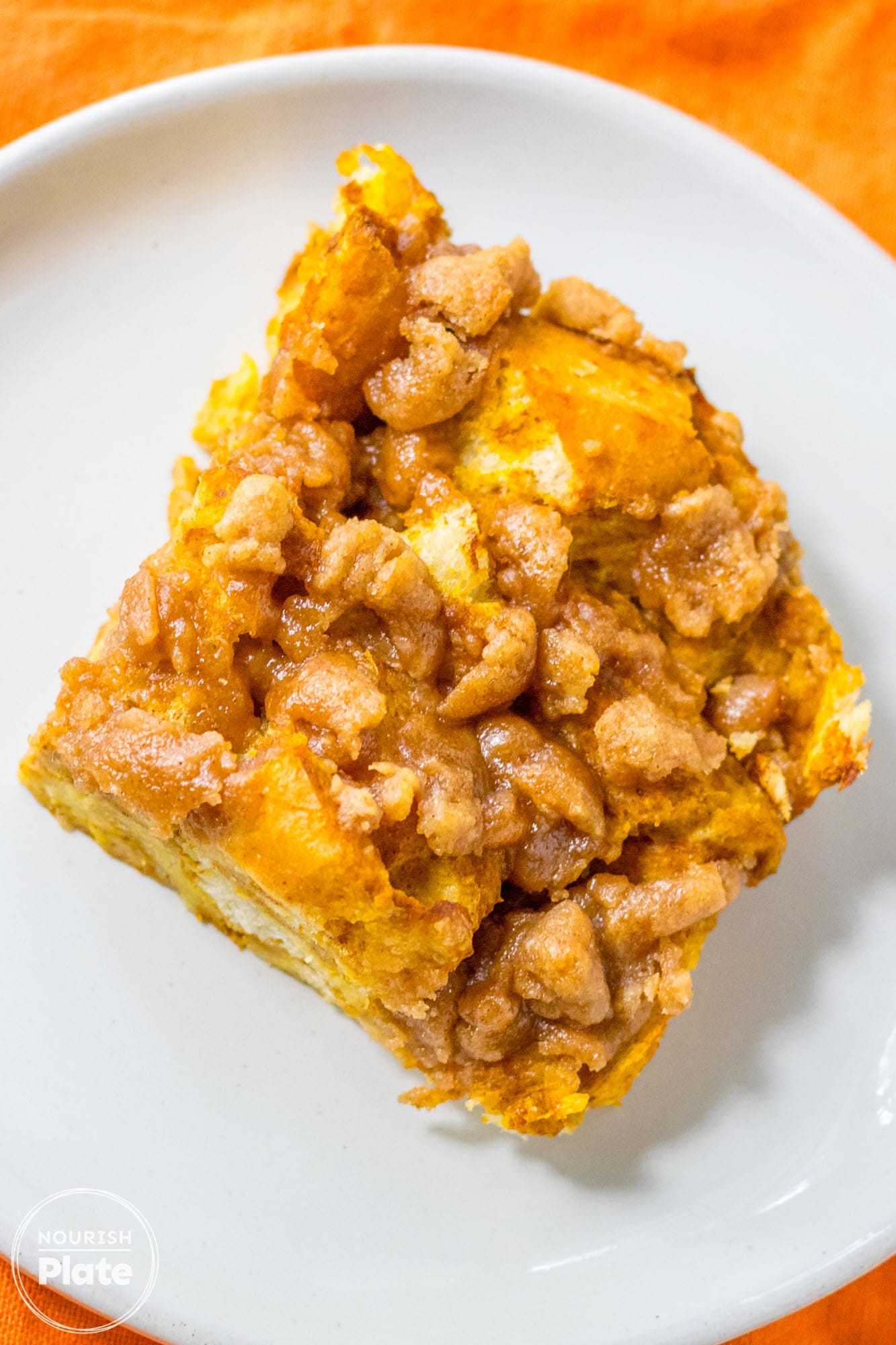 Overhead shot of a piece of pumpkin french toast casserole served on a small white plate