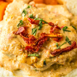 Creamy tuscan pork chops served over mashed potatoes on a plate