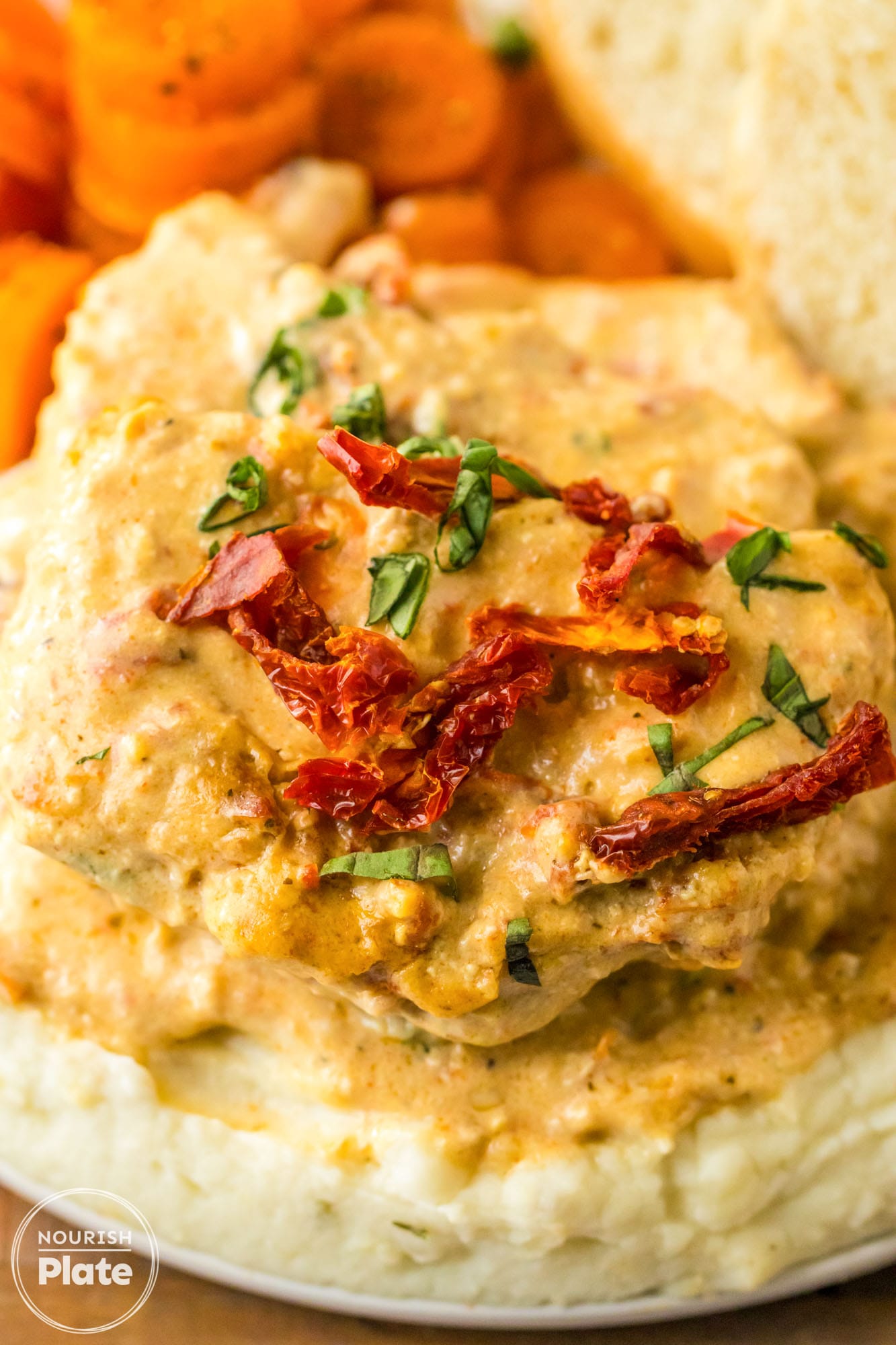 Creamy tuscan pork chops served over mashed potatoes on a plate