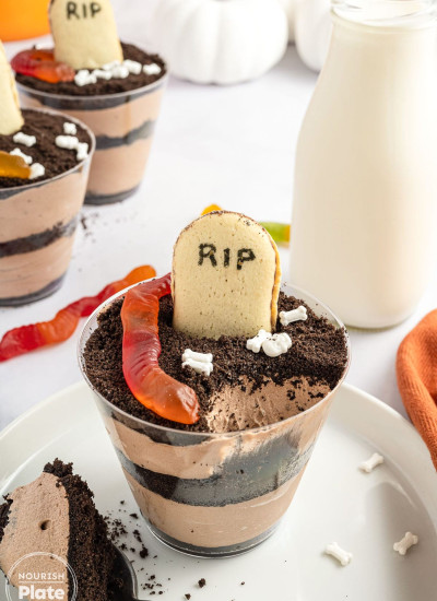 Pudding dirt cups in plastic cups, with a bottle of milk in the background