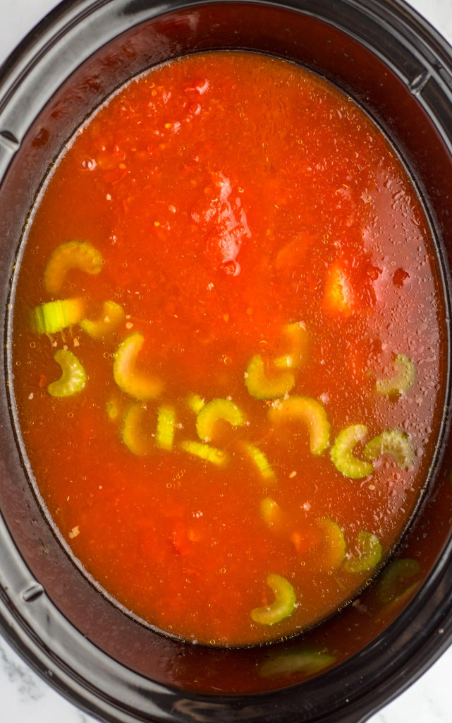 Soup in the slow cooker, showing tomato sauce and sliced celery