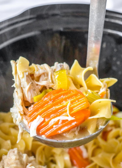 A ladle with chicken noodle soup