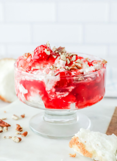 Cherries in the Snow served in a serving glass with a spoon on the side, with a crunchy pecan topping