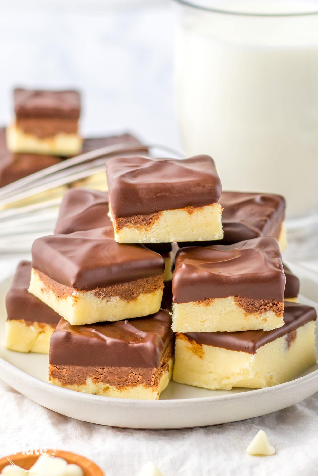 Stacked boston cream pie fudge pieces stacked on a white serving plate.