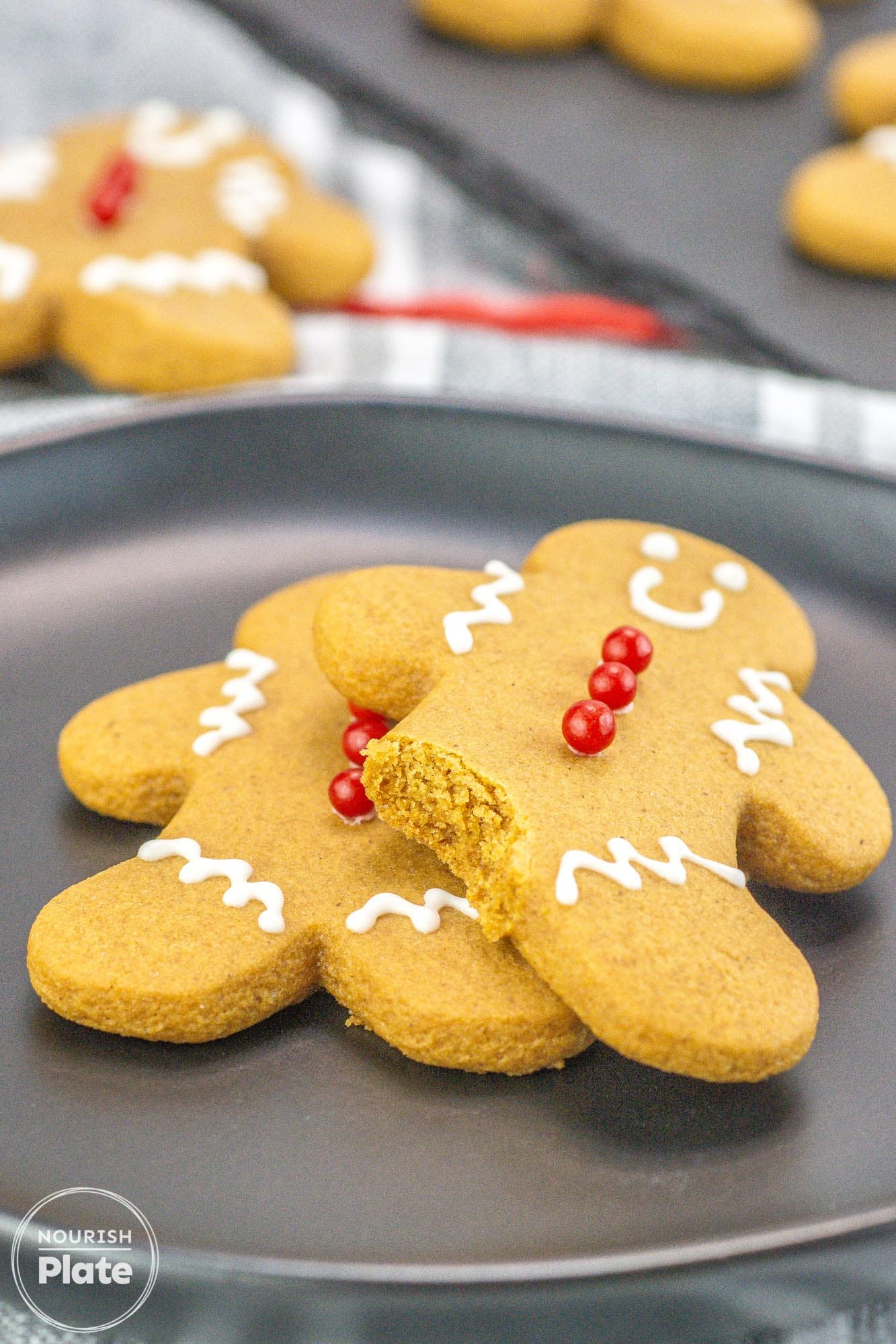 Gingerbread men cookies on a black plate, showing a bite shot