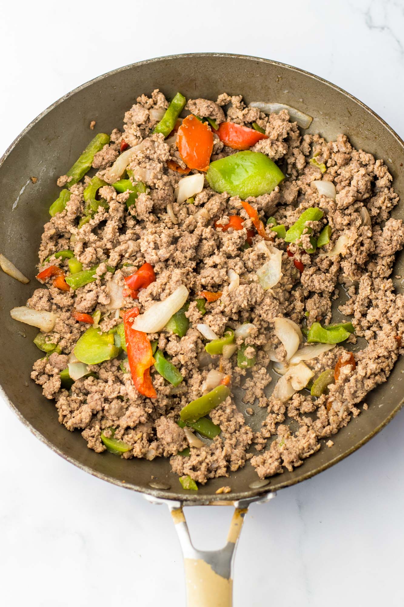 cooked ground beef and veggies cooked in a skillet