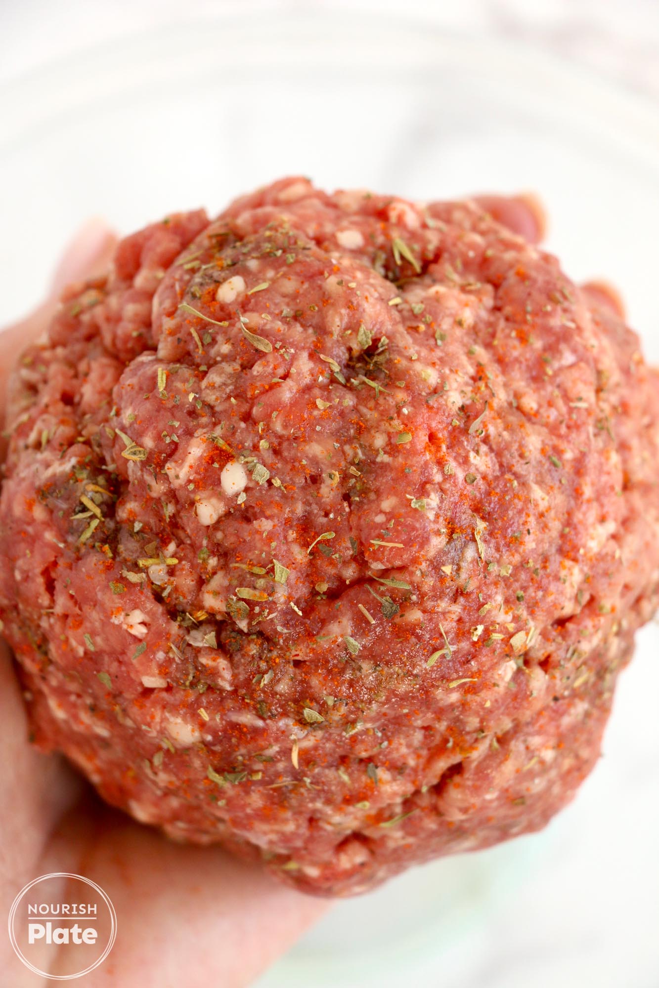 Seasoned raw meatloaf meat shaped into a ball