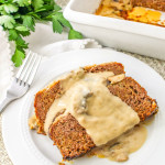 2 slices of mushroom meatloaf with gravy served on a white plate