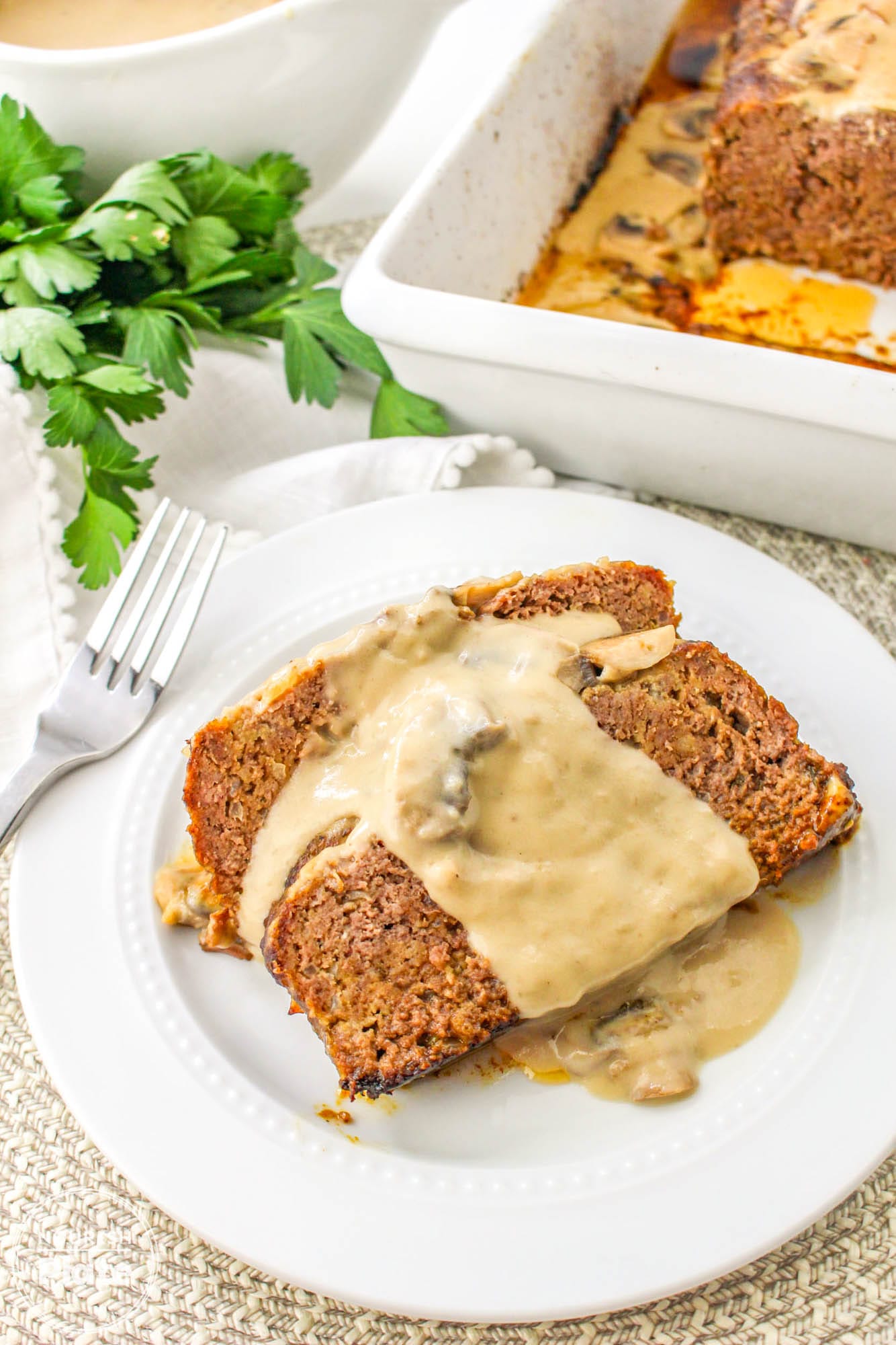 2 slices of mushroom meatloaf served on a white plate, with creamy mushroom gravy on top