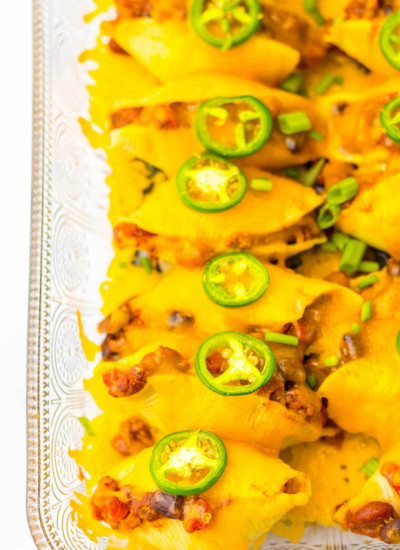 overhead shot of chili stuffed shells baked in a glass pan, topped with cheese and jalapeno slices