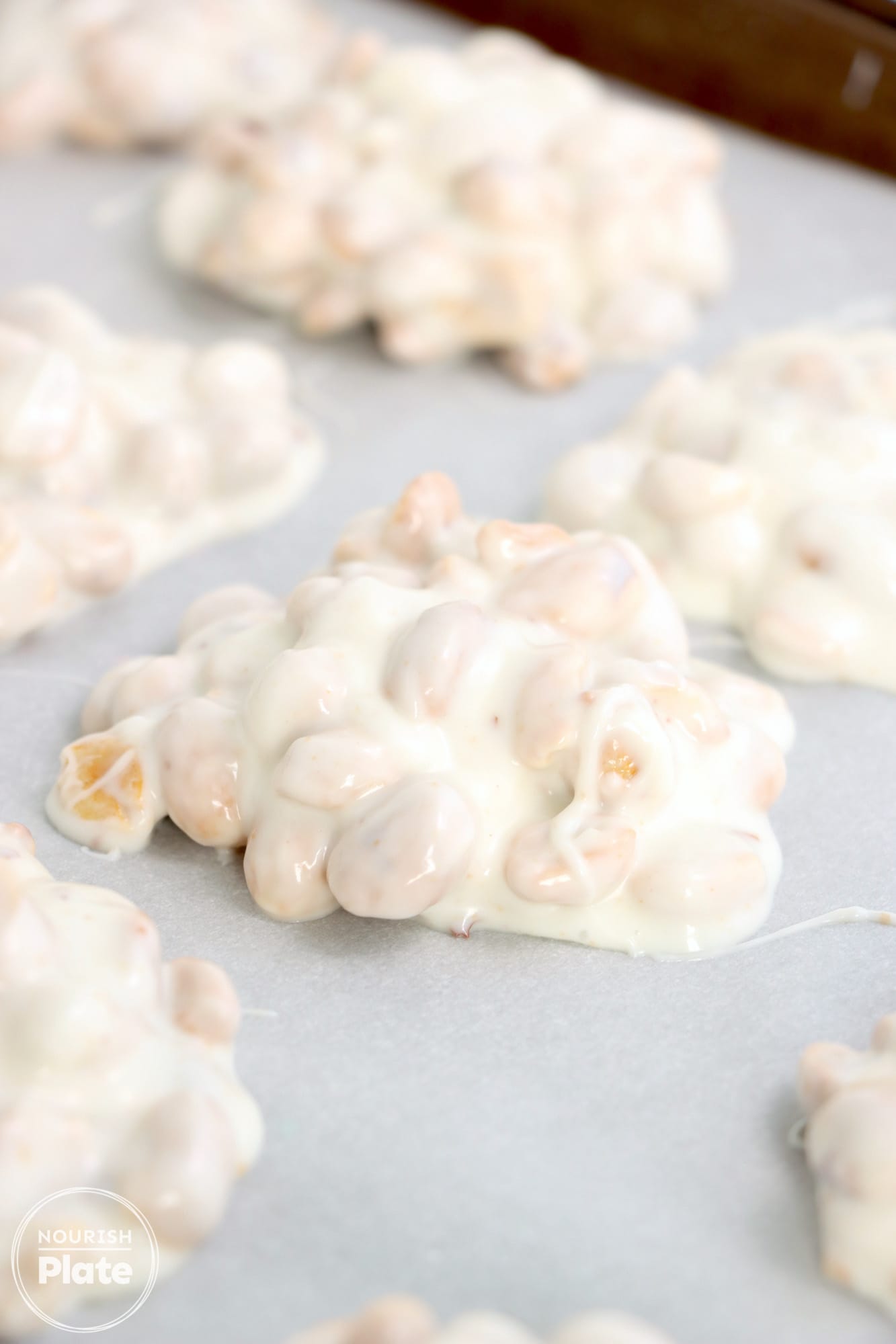 Spooned crockpot candy on parchment paper creating clusters
