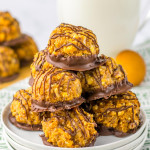 Stacked Samoas truffles on a white plate, with a glass of milk in the background