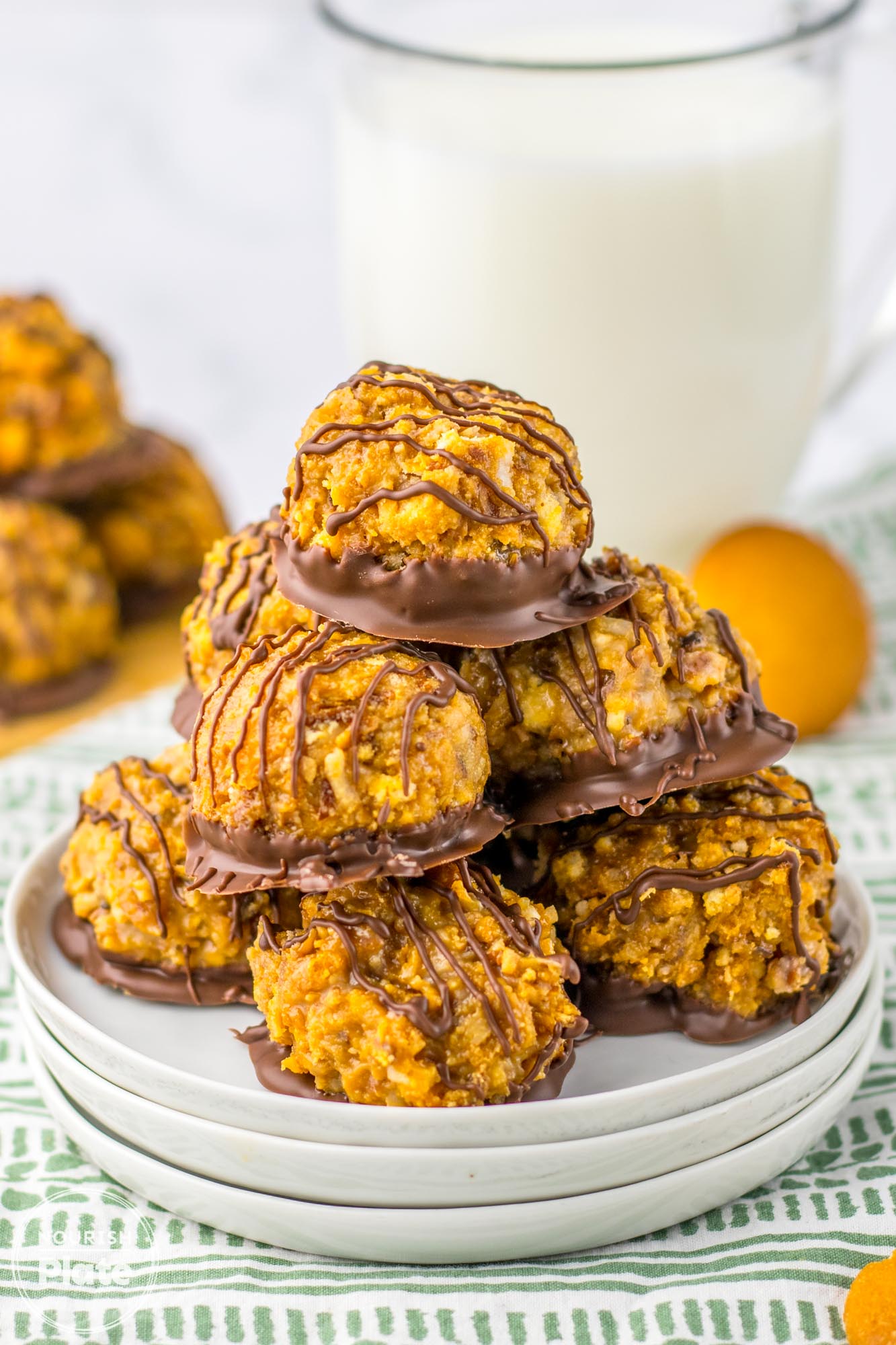 Stacked Samoas truffles on a white plate, with a glass of milk in the background