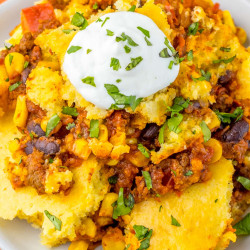 Plated portion of cornbread casserole topped with a dollop of sour cream